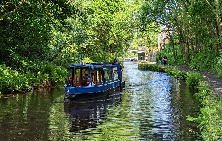 Looking back towards Marsden along the Huddersfield Narrow Canal. The boat is the shuttle service from Marsden station to the canal tunnel and visitor centre.