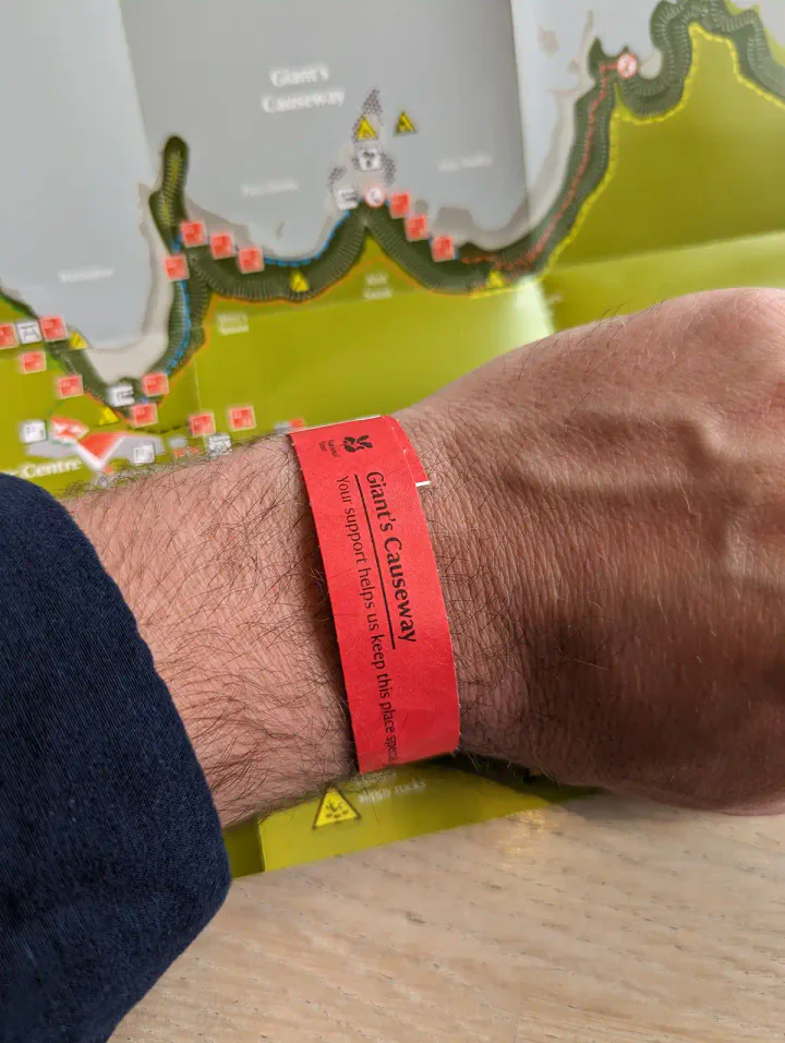 A man's wrist with a Giant's Causeway visitor centre wristband