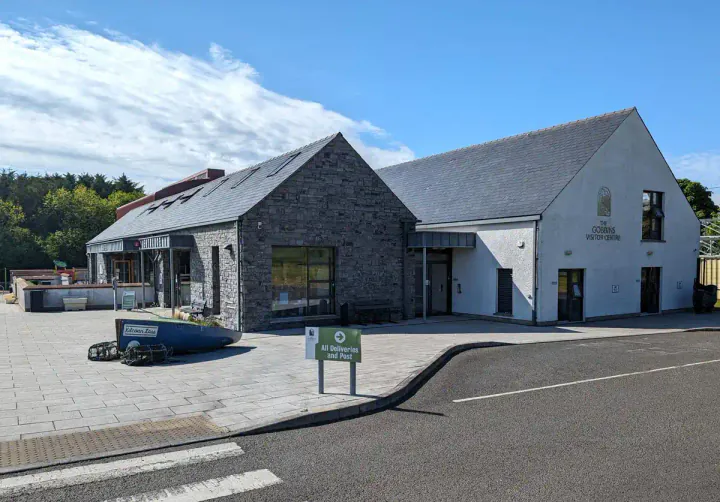 The Gobbins visitor centre. A modern building, with the entrance and cafe at the front. There's a small wooden boat set into the pavement in front of the building.