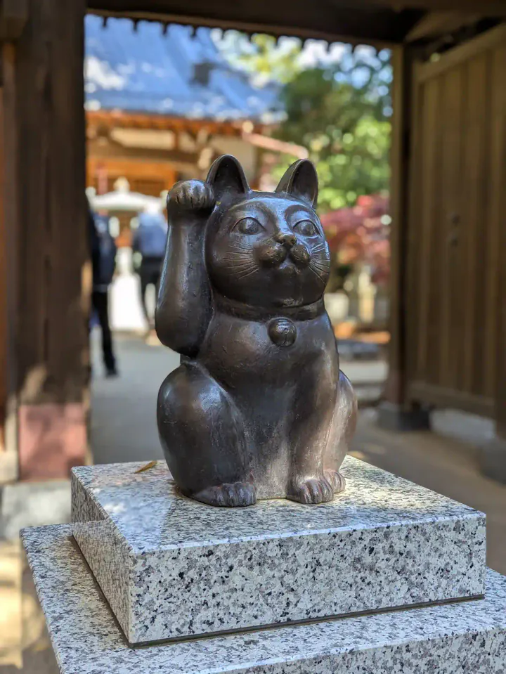 A bronze lucky cat statue at the entrance to Gōtokuji Temple in Tokyo