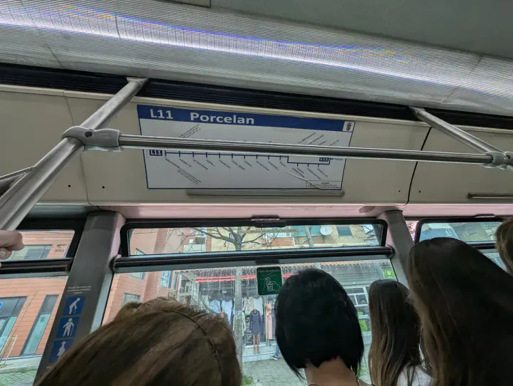 On the number 11 bus to Porcelan and Bunk'Art 1. People are stood holding on to the handrail. There's a bus map above the window showing the loop that the bus does at the end of the route.