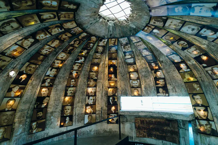 The domed roof of a concrete bunker with rows of photographs. There's a hole in the roof, as if the bunker has come under bombardment.