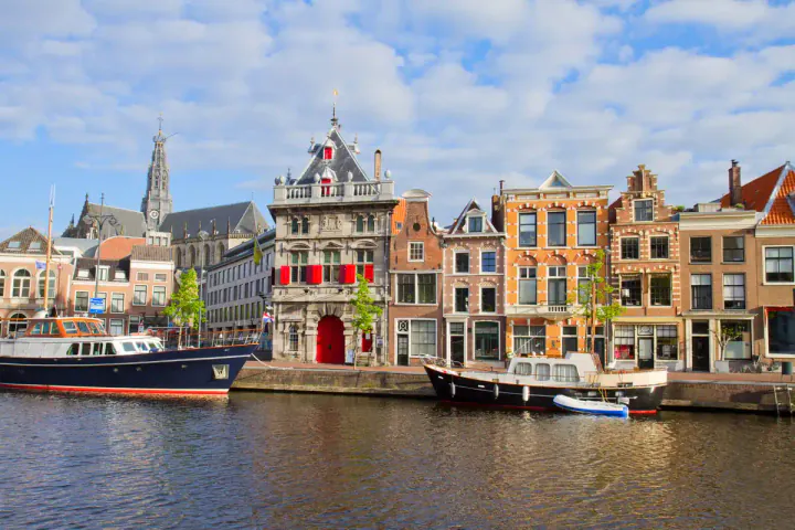 A row of colourful medieval buildings along a river, with boats in front