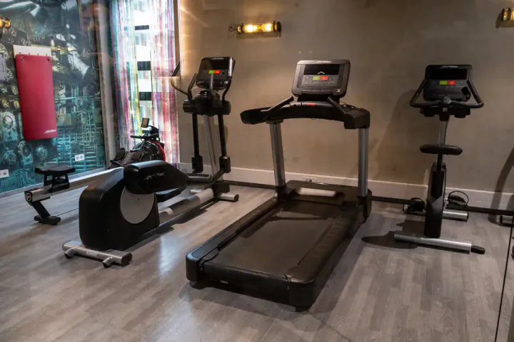A small hotel gym with treadmill, weights and other gym equipment