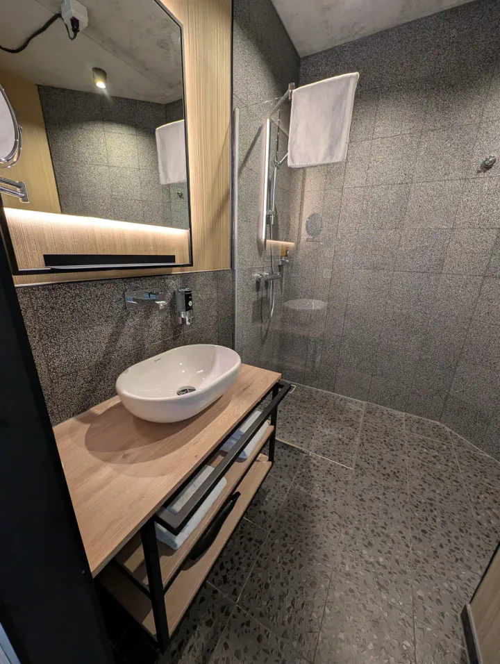 A bathroom with concrete-style wall and floor tiles