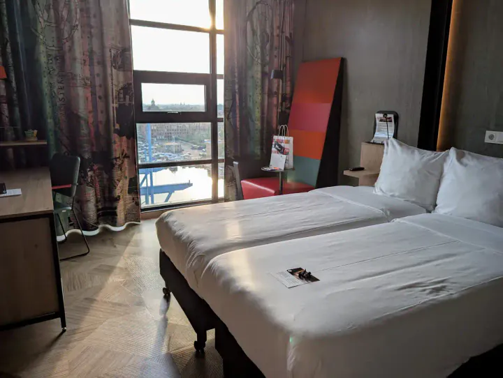 A hotel room with floor to ceiling windows on a high floor