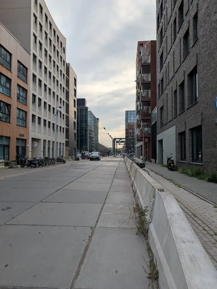 A long straight street with modern apartment buildings and industrial relics