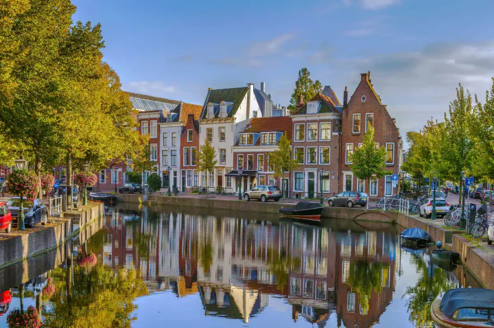 Canal houses reflecting in the still waters of a canal in Leiden