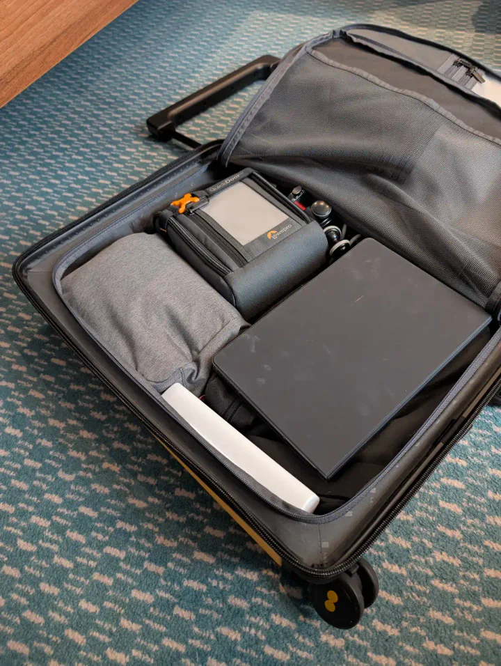 A suitcase packed with packing cubes and electronics