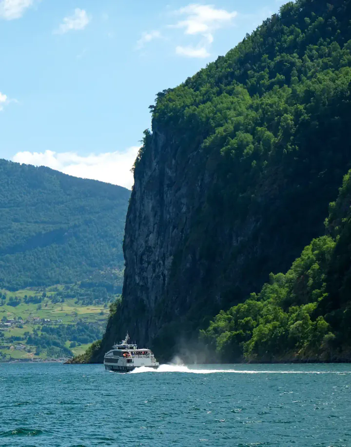 A ship passing a tall cliff on a Norwegian fjord