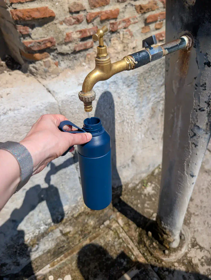 Filling a water bottle from a brass outdoor tap