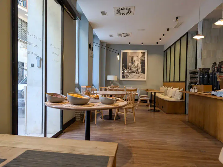A coffee shop set up for breakfast, decorated in light wood and calming green tones