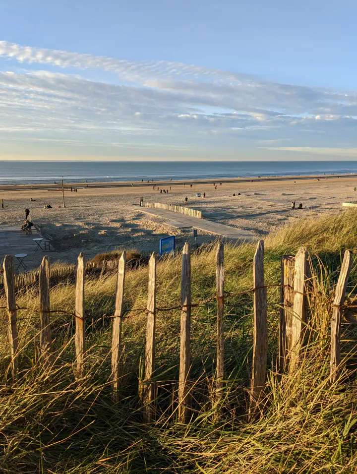 A wide sandy beach at golden hour, with the sea beyond
