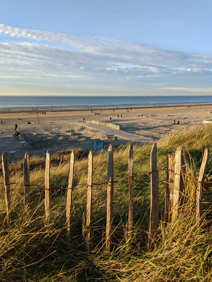 A wide sandy beach at golden hour, with the sea beyond