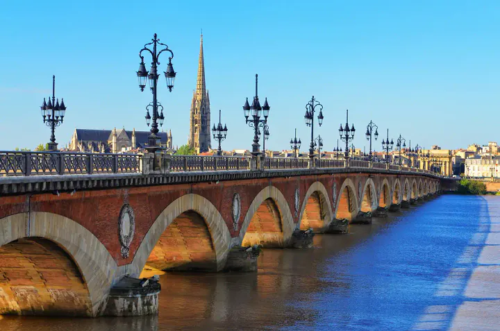 A brick and stone bridge with lots of arches, crossing a wide river