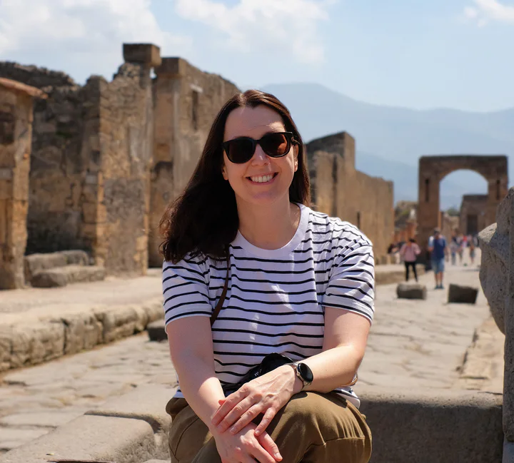 A picture of a woman sat on a stone on a street in Pompeii