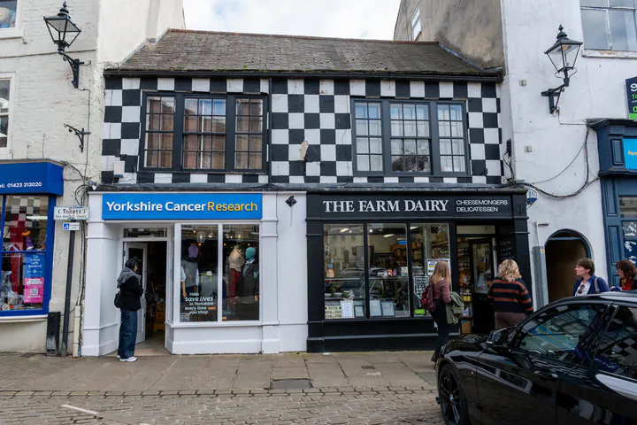 Two shops on Knaresborough's Market Place. The top half is painted with black and white checks.