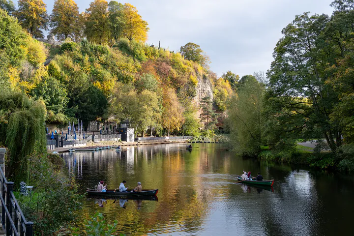A view of the riverside in Knaresborough. There are rowing boats on the river and the trees are changing colour for autumn.