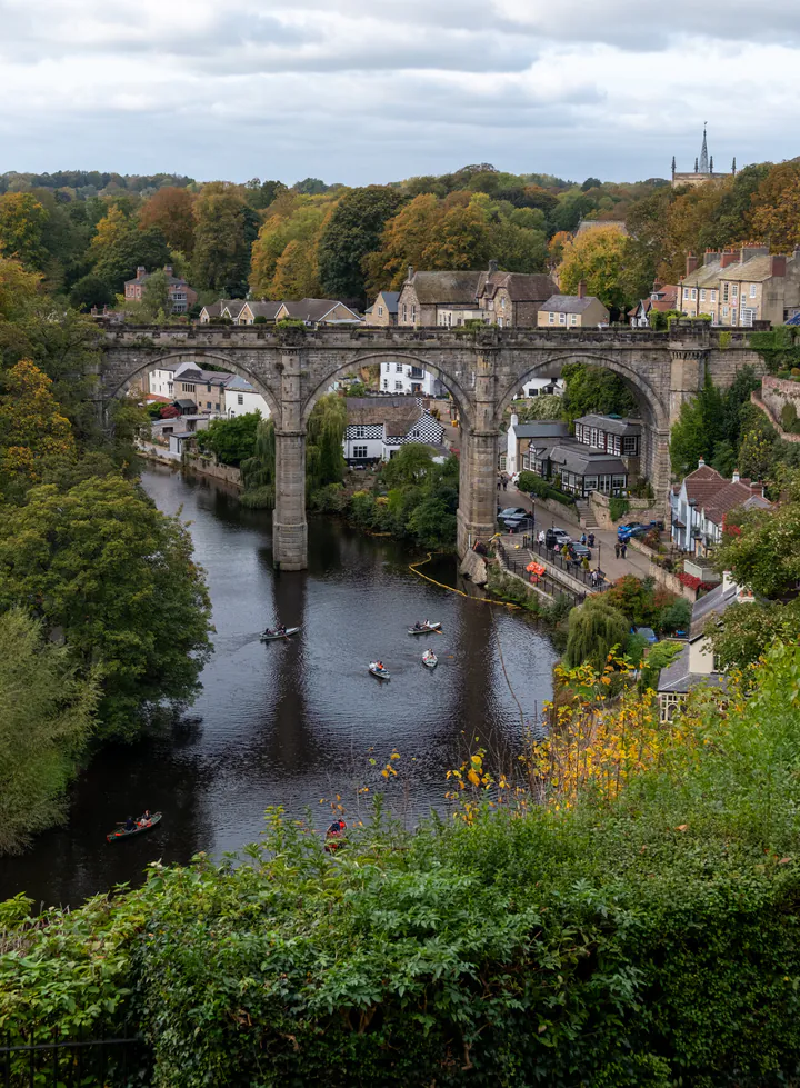 Knaresborough railway viaduct spanning the River Nidd, with stone houses huddled on the riverside. This image was taken from Knaresborough Castle; the viaduct, castle and river together are three of the best things to do in Knaresborough.