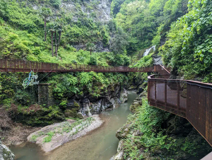 A wooded ravine with a waterfall and a river in the bottom. There are walkways around the edges.
