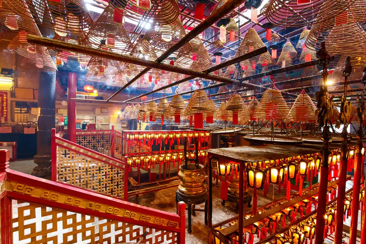 Inside Man Mo Temple in Hong Kong. There are coils of incense hanging from the ceiling and red accents everywhere.