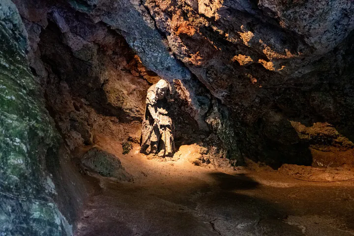 A statue of a hunched old woman inside a cave