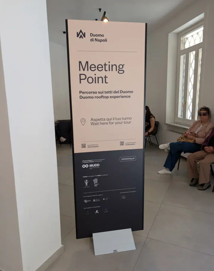 A sign inside a building showing where to meet for the rooftop tour