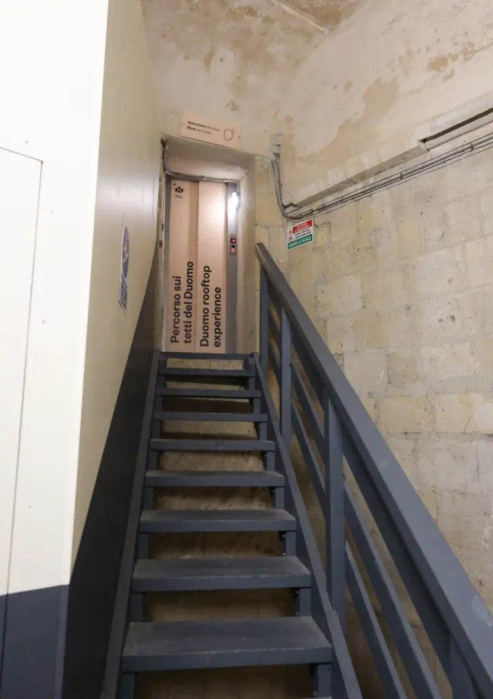 A flight of metal steps up to a narrow lift door.