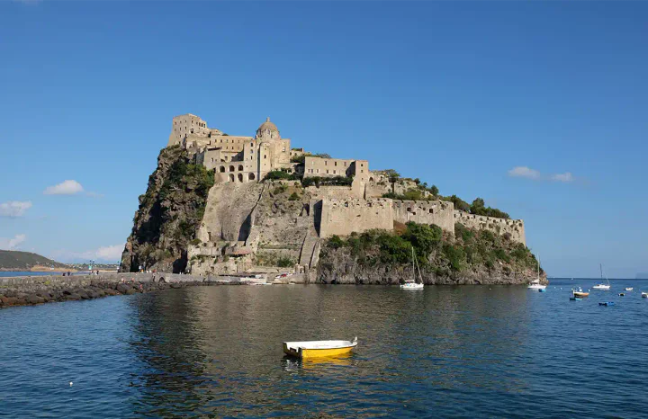 A castle on a rocky island in the middle of the sea. It's connected to the mainland by a narrow causeway.