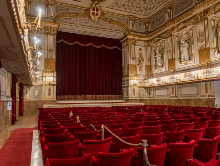 A theatre with red velvet seats and ornate wall decoration