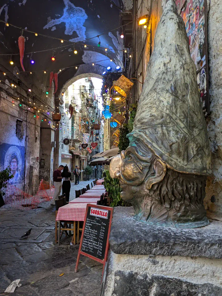 Naples in a nutshell - a pizza restaurant in the street, Pulcinella and a Maradona mural