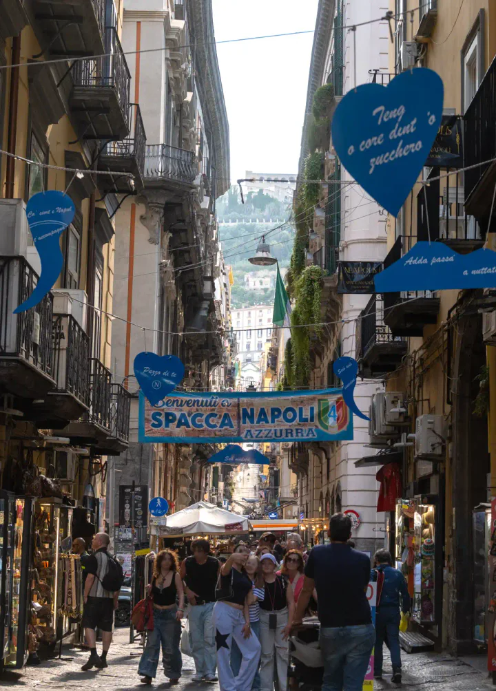 The long, straight Spaccanapoli street in Naples, with Castel Sant'Elmo on the hill in the background