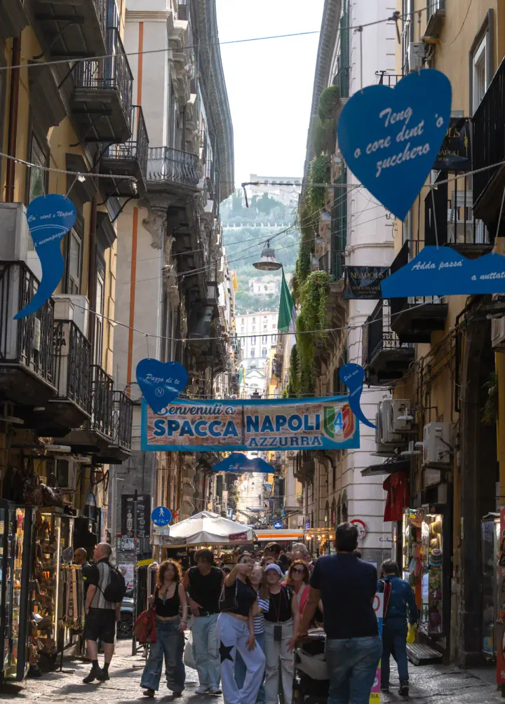 The long, straight Spaccanapoli street in Naples, with Castel Sant'Elmo on the hill in the background