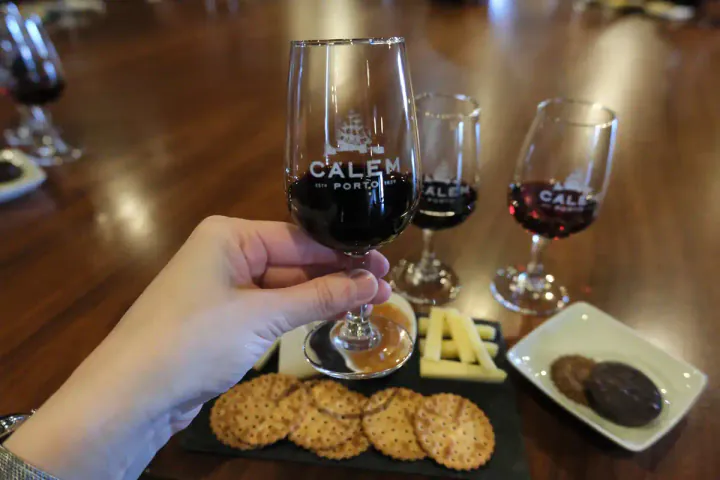 My hand picking up a glass of port wine at the Calem cellar