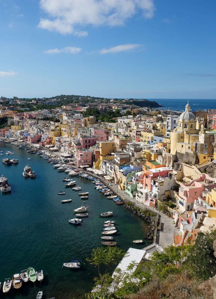 A stunning view of fishing village with houses and a domed church painted in pink, yellow, mint and blue