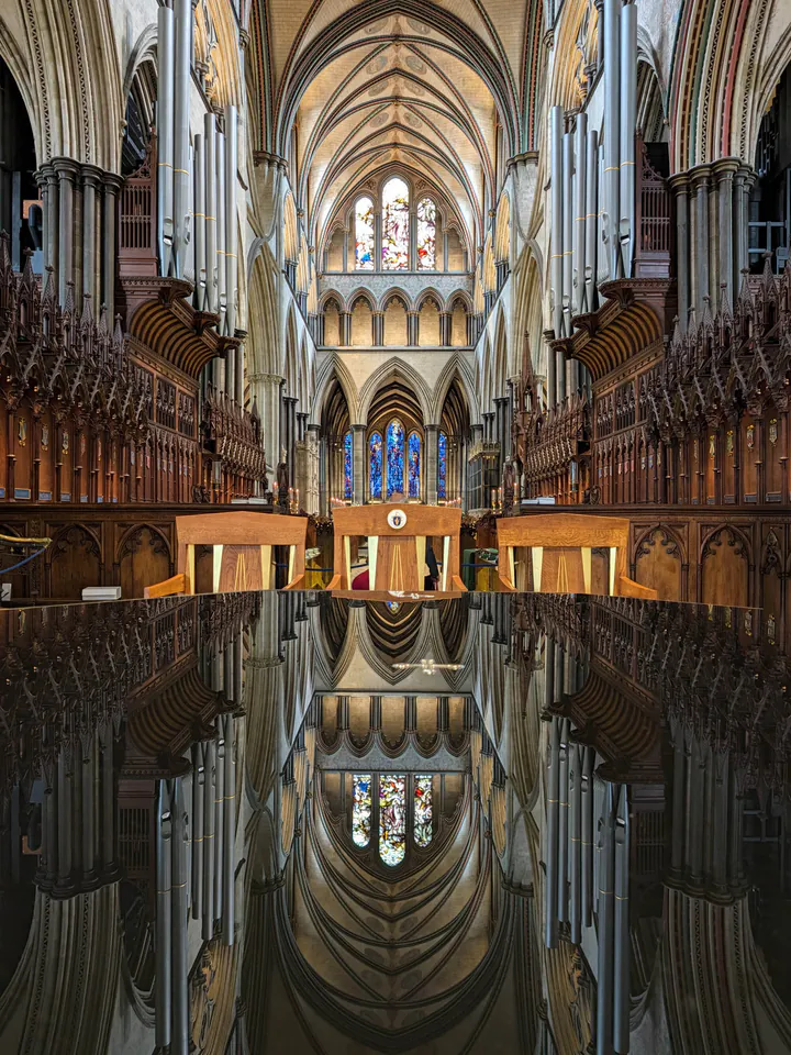 An ornate church ceiling reflected in a shiny black altar