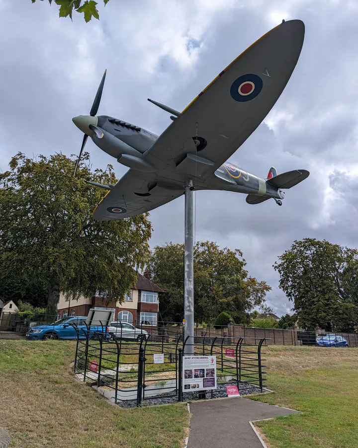 A full-size Spitfire sculpture mounted on a pole in a park