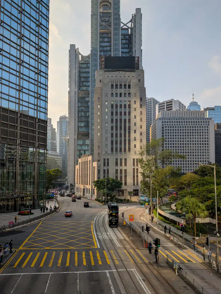 Tall buildings dwarfing the traffic below on a sunny day in Hong Kong