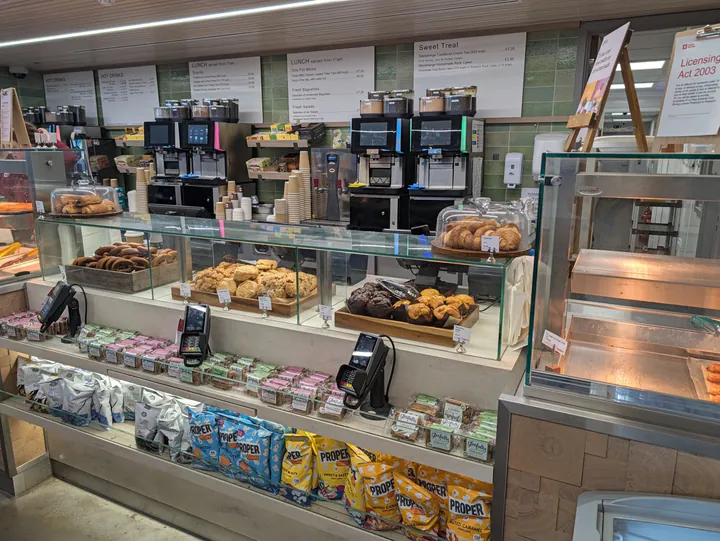 A cafe counter with pastries, muffins and coffee machines