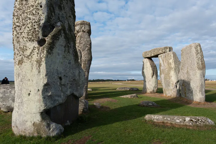 Huge stones at Stonehenge, with long shadows showing that it's early in the day