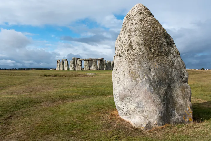 A large stone with Stonehenge in the background