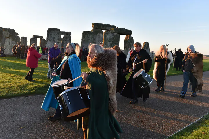 People in ceremonial dress with drums and other instruments at Stonehenge for the Autumn Equinox