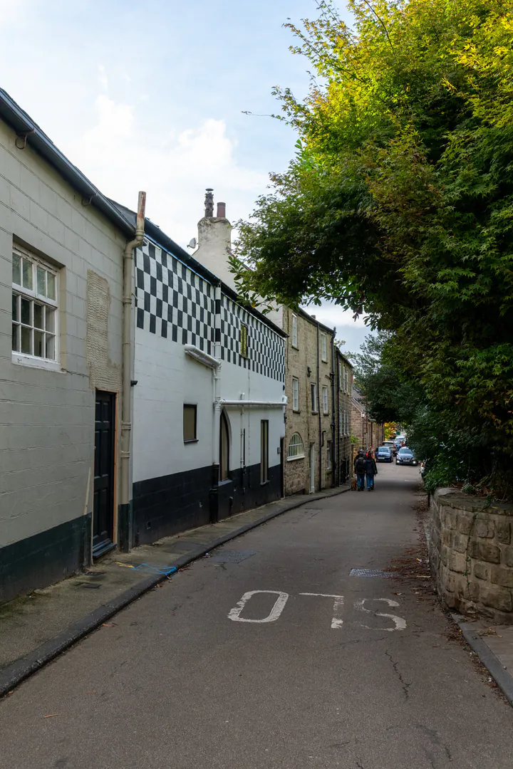 A row of old houses on a narrow street. The middle house is painted with black and white checks.