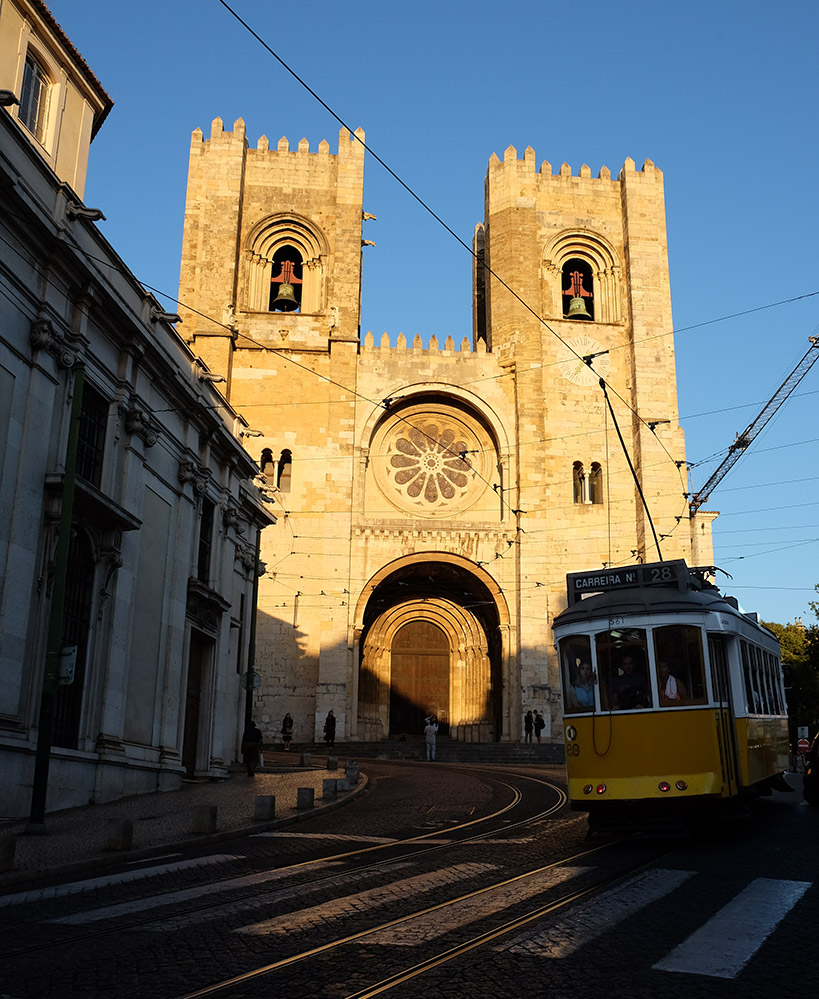 One of Lisbon's famous yellow trams in front of the lovely cathedral