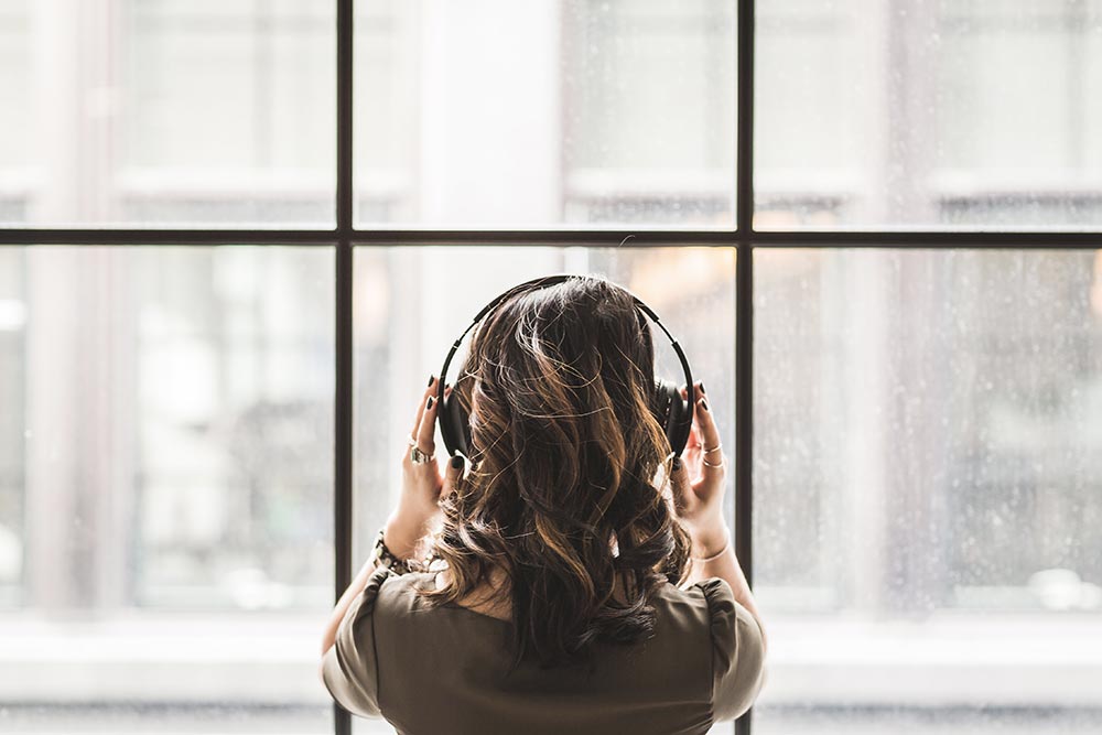 A woman listening to a travel podcast through headphones