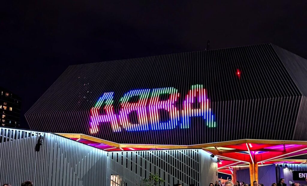 The ABBA Arena in Stratford, London. A brightly coloured ABBA logo is on top of a large black arena building