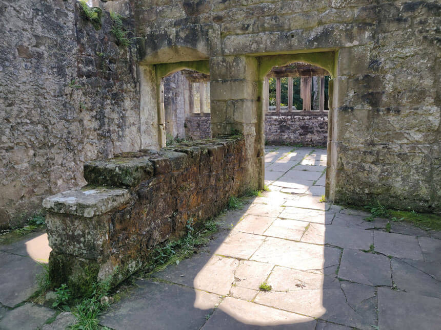 Wycoller is one of England's most haunted villages. Two arched doorways in a ruined stone house. The sun is shining through the doorways, making a pattern on the stone flagged floor.