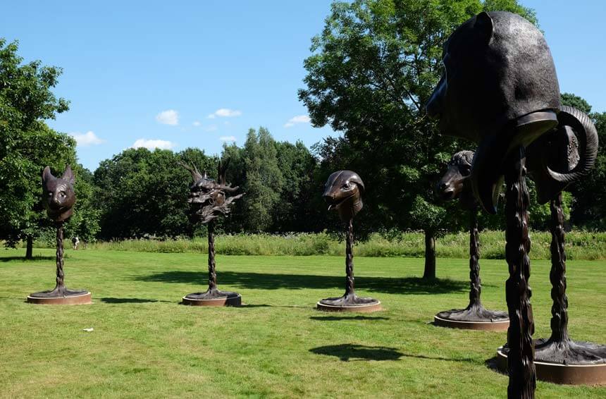 Ai Weiwei's Circle of Animals / Zodiac Heads. A series of bronze animal heads depicting the Chinese zodiac signs stand on poles in a grassy park. They are set in a circle. 