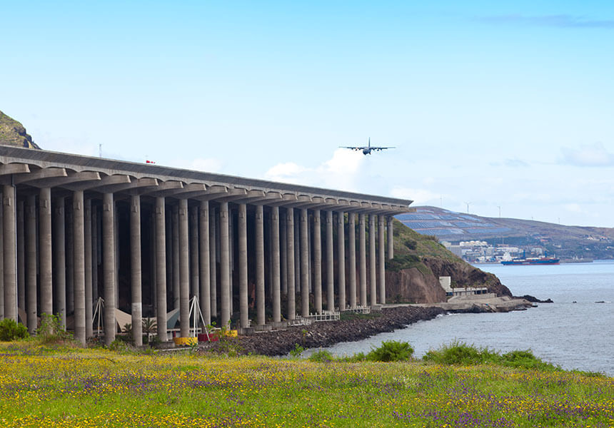 The runway at Madeira's airport, with a plane approaching over the sea. My top tip for visiting Madeira is to plan for flight delays.