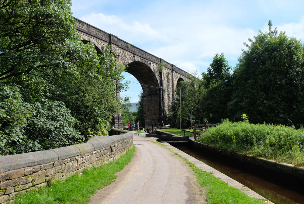 The railway viaduct in Uppermill carries trains high over the Huddersfield Narrow Canal
